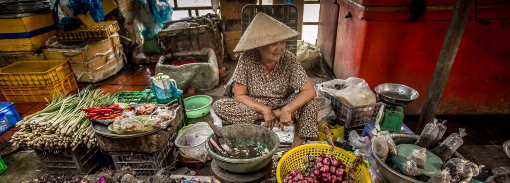 En bild på en kvinna som säljer grönsaker